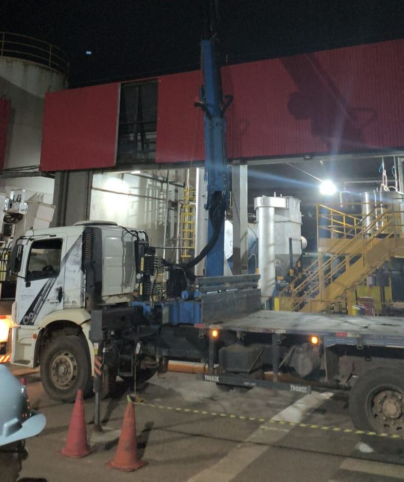 Caminhão Munck operando à noite em planta industrial